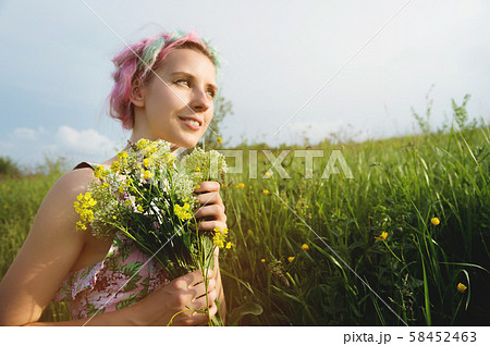Portrait of a young happy smiling girl in a cotton dress with a bouquet of wildflowers 58452463