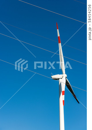 Renewable energy - Red and white wind turbine and a power line Renewable energy - Red and white wind turbine and a power line 58454256