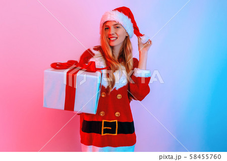 Happy girl in Santa hat holding big gift box Happy girl in Santa hat holding big gift box 58455760