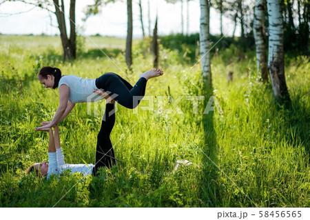 two woman on field doing fitness yoga exercise together 58456565