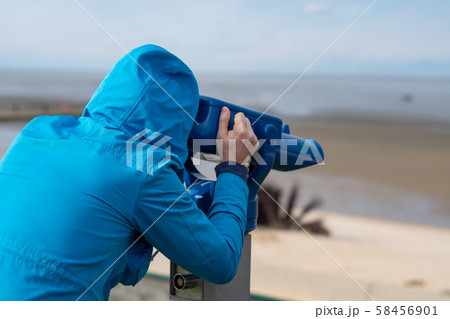 Man in blue coat looking on sea using coin operated binocular viewe Man in blue coat looking on sea using coin operated binocular viewe 58456901