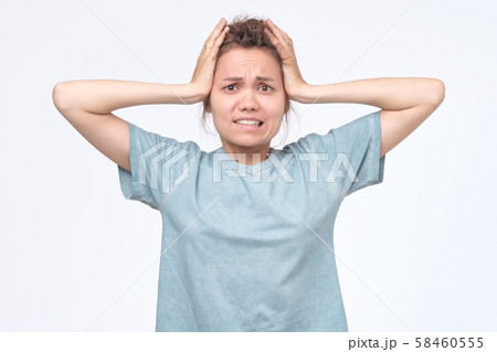 Girl screaming in terror with hands on her head, looking in panic at the camera. 58460555