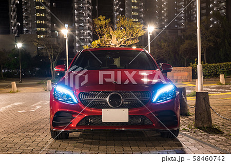 ワインレッドの車と夜の街並み風景の写真素材