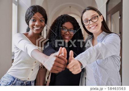 Three happy mixed-race female students showing thumbs up Three happy mixed-race female students showing thumbs up 58463563