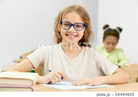 Smart girl posing while doing task during lesson Smart girl posing while doing task during lesson 58464605