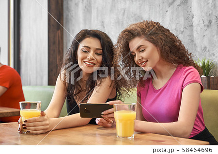 Two girls sitting in cafe, drinking juice and doing selfie 58464696