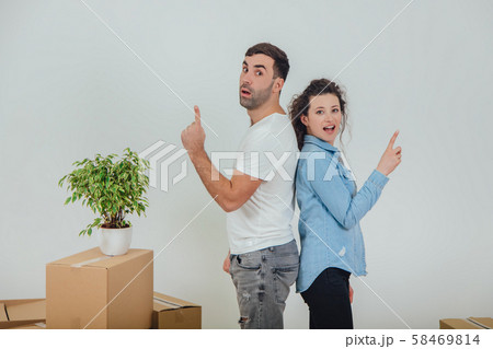 Happy wife and husband standing back to back, smiling pointing their fingers up, looking surprised. Happy wife and husband standing back to back, smiling pointing their fingers up, looking surprised. 58469814