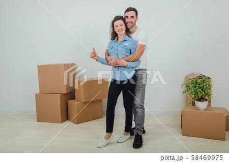 Couple moving into their new house, husband is hugging his wife, looking at the camera, smiling Couple moving into their new house, husband is hugging his wife, looking at the camera, smiling 58469975