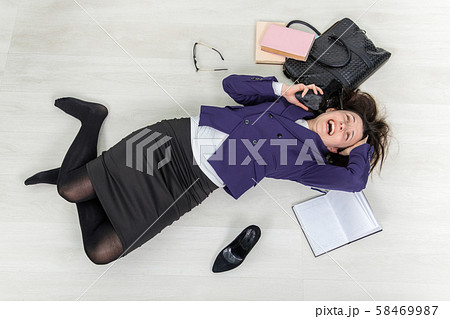 Young teacher is looking out of mind, lying on thr floor, holding her shoe near ear, as if it was Young teacher is looking out of mind, lying on thr floor, holding her shoe near ear, as if it was 58469987