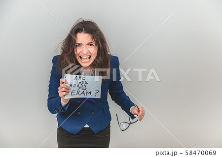 Totally tired young teacher is standing, holding a sheet of paper with ready for exam written on it Totally tired young teacher is standing, holding a sheet of paper with ready for exam written on it 58470069
