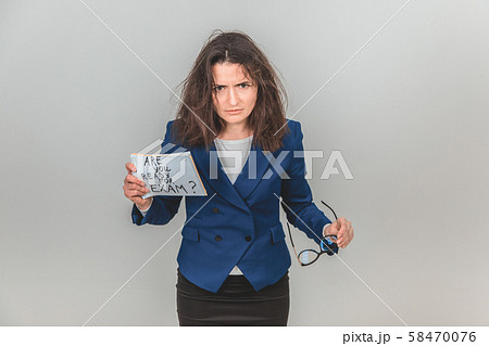 Totally tired young teacher is standing, holding a sheet of paper with ready for exam written on it Totally tired young teacher is standing, holding a sheet of paper with ready for exam written on it 58470076