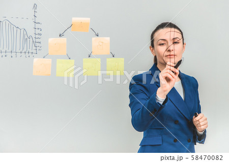 Inspired woman in formal suit, drawing dollar sign on the glass. Inspired woman in formal suit, drawing dollar sign on the glass. 58470082