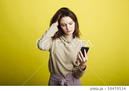 Image of happy young girl standing isolated on yellow background reading messages on phone 58470514