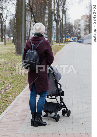 Girl walks in the park with a baby carriage. 58480703