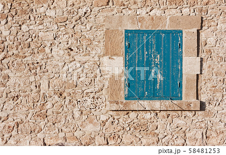 Antique wall of stone and blue wooden shutters on 58481253