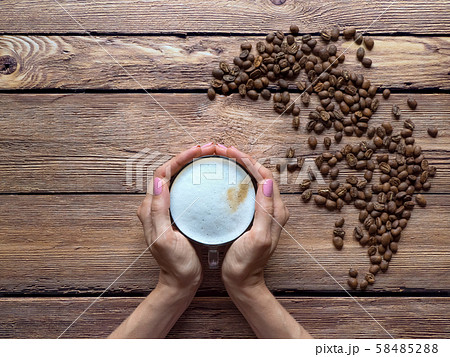 Coffee in a paper cup is on the brown table. Coffee in a paper cup is on the brown table. 58485288