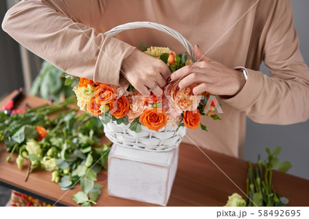 Florist woman creates flower arrangement in a wicker basket. Beautiful bouquet of mixed flowers 58492695