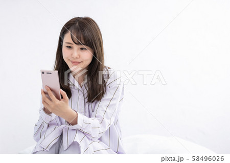 スマホを見る女性 寝室 ベッド パジャマ 58496026