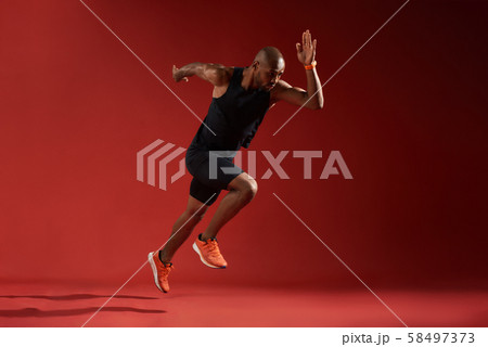 Never give up. Full length of young african man in sports clothing running in studio against red 58497373