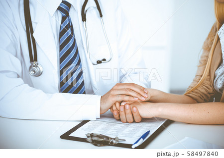 Hand of doctor reassuring her female patient. Concepts of medical ethics and trust in medicine 58497840