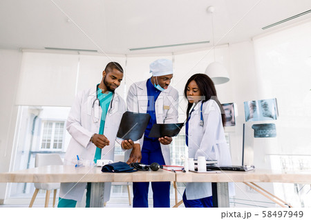 Healthcare, medical: Group of three young African doctors, two men and woman, discuss and looking x Healthcare, medical: Group of three young African doctors, two men and woman, discuss and looking x 58497949