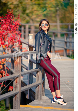 Fall concept - beautiful woman drinking coffee in autumn park under fall foliage 58498396