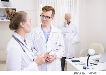 Two young colleagues in whitecoats discussing medical stuff in clinics Two young colleagues in whitecoats discussing medical stuff in clinics 58501966