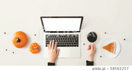 Person using a laptop computer with pumpkins 58502257