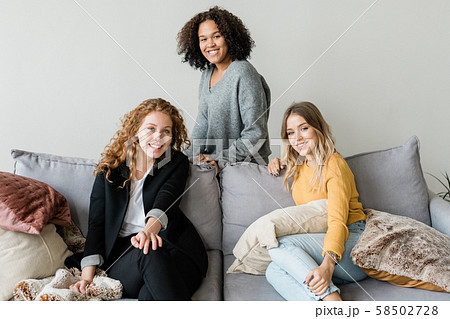 Group of cheerful friendly girls relaxing on soft comfortable sofa Group of cheerful friendly girls relaxing on soft comfortable sofa 58502728