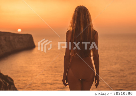 Young woman staying on mountain on shore in body Young woman staying on mountain on shore in body 58510596