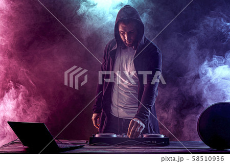 Trendy male dj posing against mixing console 58510936