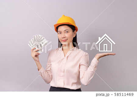 loans for real estate concept, woman with yellow helmet holding banknote money in hand and white logo home icon in another hand 58511469
