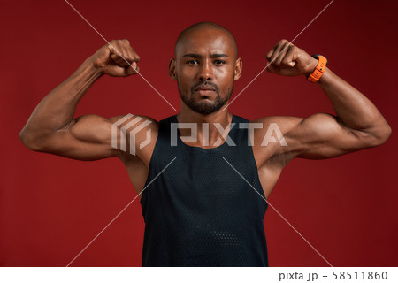 I am strong and healthy. Portrait of handsome afro american man showing his biceps and looking at 58511860