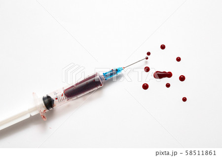 Closeup of a disposable syringe and many blood drops isolated on white 58511861
