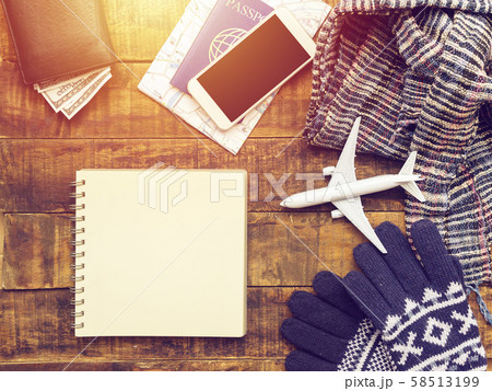 flat lay of passport ,mobile phone , plane model , scarf , gloves and traveler's accessories items on wooden background with blank paper for copy space. travel and vacation concept flat lay of passport ,mobile phone , plane model , scarf , gloves and traveler's accessories items on wooden background with blank paper for copy space. travel and vacation concept 58513199