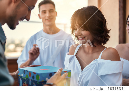 This is for you Young happy man is receiving a gift from beautiful and cheerful female friend while This is for you Young happy man is receiving a gift from beautiful and cheerful female friend while 58513354