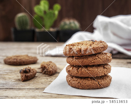 stack of chocolate chip cookies on white napkin paper on wooden table decorate with cactus at background 58513653