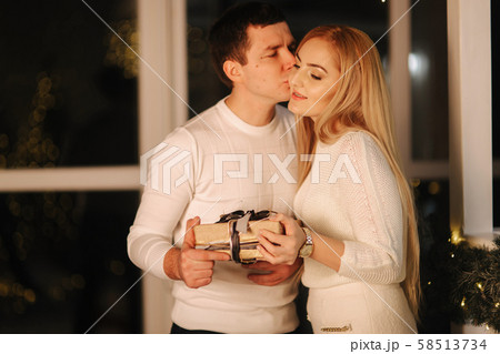 Husband gives present for his wife, background of window. Happy woman take present Husband gives present for his wife, background of window. Happy woman take present 58513734