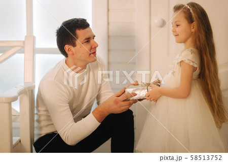 Father with daughter in Christmas time. Dad give a present for his little cure daughter 58513752