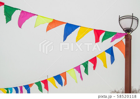 Colorful triangular cloth flags hanging on ropes tied to a lamppost, decoration for festival Colorful triangular cloth flags hanging on ropes tied to a lamppost, decoration for festival 58520118
