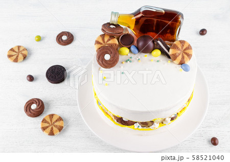 funny cake with a bottle of alcohol, candy and cookies on wooden table funny cake with a bottle of alcohol, candy and cookies on wooden table 58521040