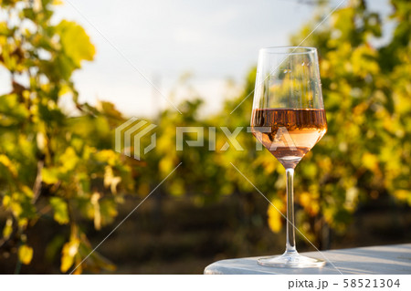 glass of rose wine on a table in the vineyard with glass of rose wine on a table in the vineyard with 58521304