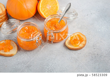 Homemade pumpkin and orange confiture in a jars on a gray concrete background. Homemade pumpkin and orange confiture in a jars on a gray concrete background. 58523309