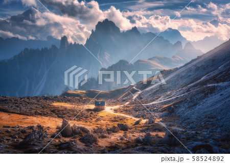 Small house in beautiful mountain valley, orange grass, stones, blue sky with clouds at sunset  58524892
