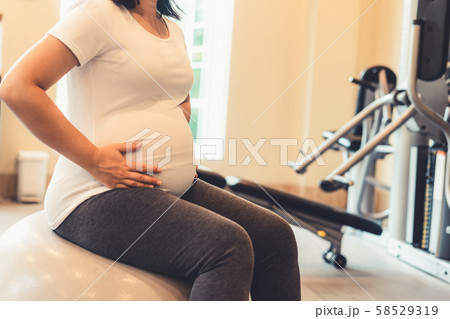 Active pregnant woman exercise in fitness center. 58529319