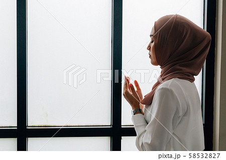 Islamic woman praying near window 58532827