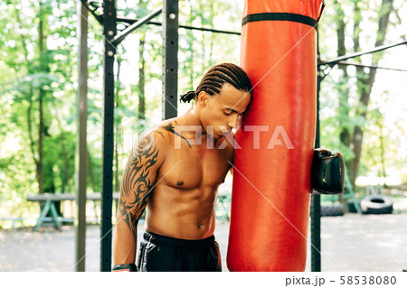 Exhausted kickboxer leaning on a punching bag Exhausted kickboxer leaning on a punching bag 58538080