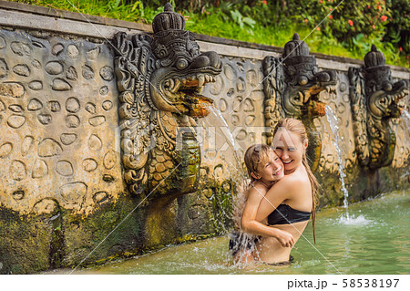 Mom and son travelers in hot springs banjar. Thermal water is released from the mouth of statues at Mom and son travelers in hot springs banjar. Thermal water is released from the mouth of statues at 58538197