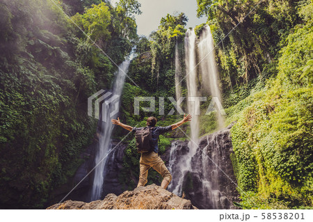 Man in turquoise dress at the Sekumpul waterfalls in jungles on Bali island, Indonesia. Bali Travel 58538201