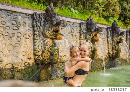 Mom and son travelers in hot springs banjar. Thermal water is released from the mouth of statues at Mom and son travelers in hot springs banjar. Thermal water is released from the mouth of statues at 58538257